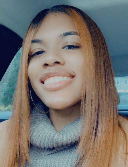 Breela Dorsey, a smiling Black woman with straight red hair wearing a gray knit turtleneck.